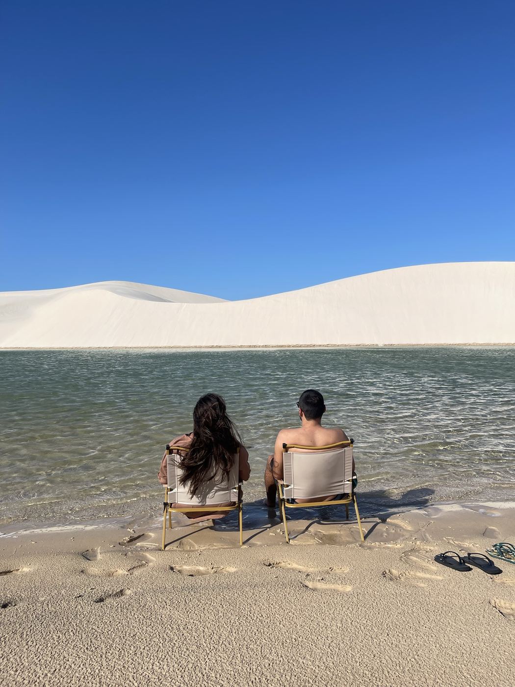 Casal sentado nas cadeiras dentro da lagoa