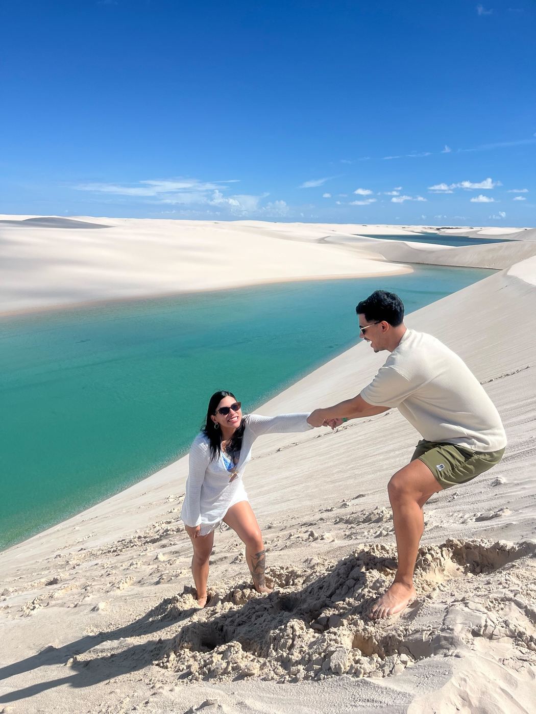 Rapaz ajudando a namorada a subir a duna
