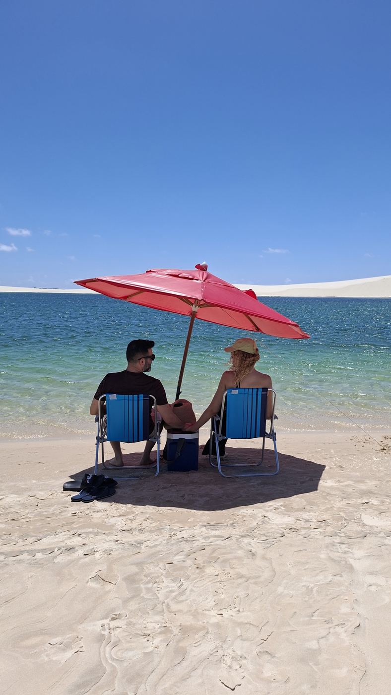 Casal sob o guarda-sol na beira da lagoa