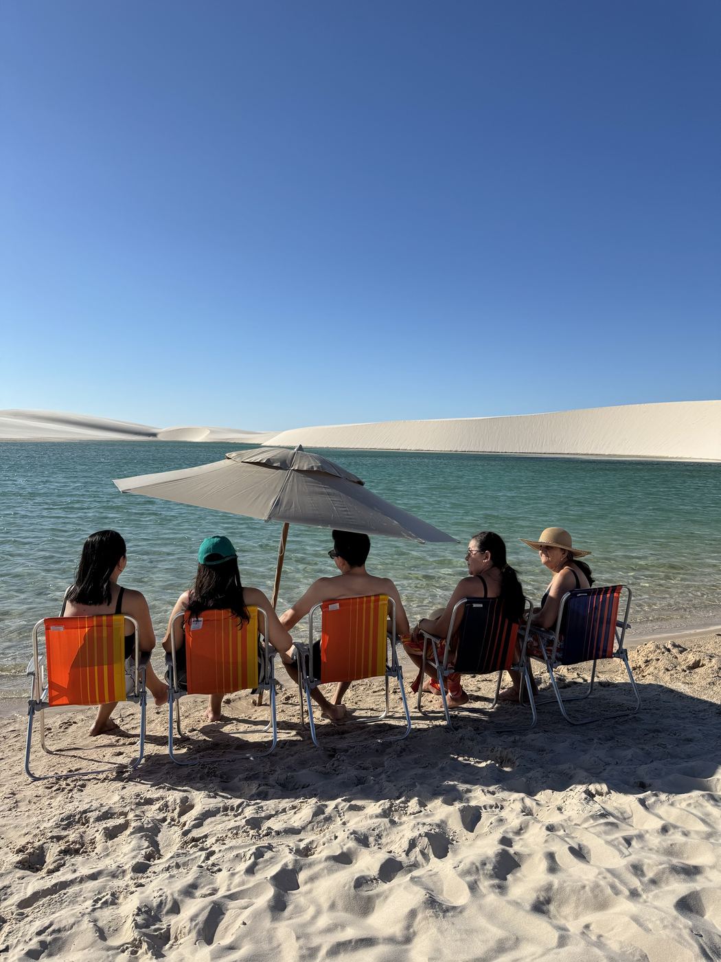 Família sentada nas cadeiras à beira da lagoa